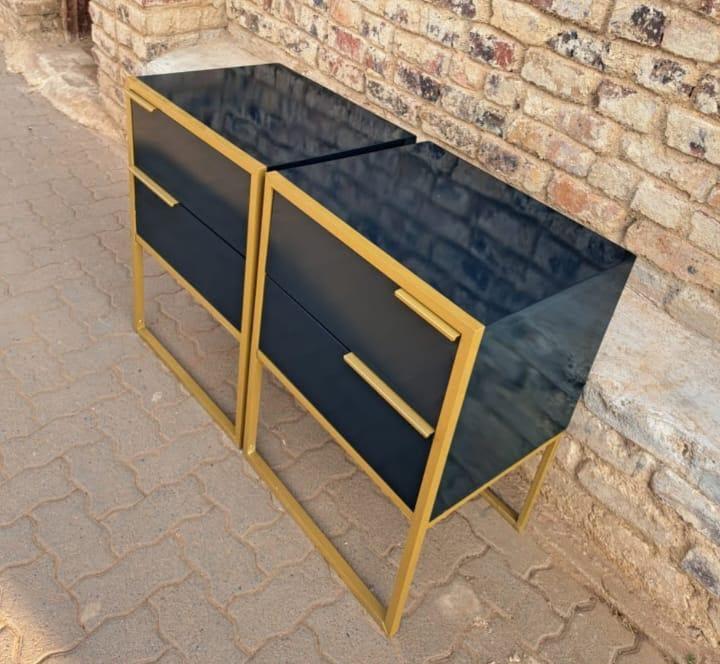 High-gloss black pedestal drawers with gold geometric frame and bar handles, sold as a pair