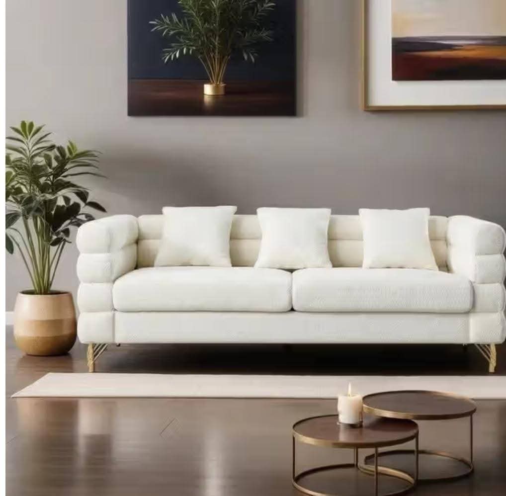 Cream bubble-back three-seater sofa with gold legs and scatter cushions in a contemporary living room