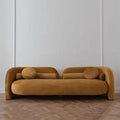 Ochre velvet organic arch sofa with rounded tubular arms and matching bolster cushions against a white wall